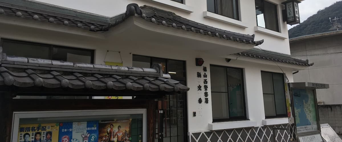 A traditional Japanese building with a tiled roof and a signboard.