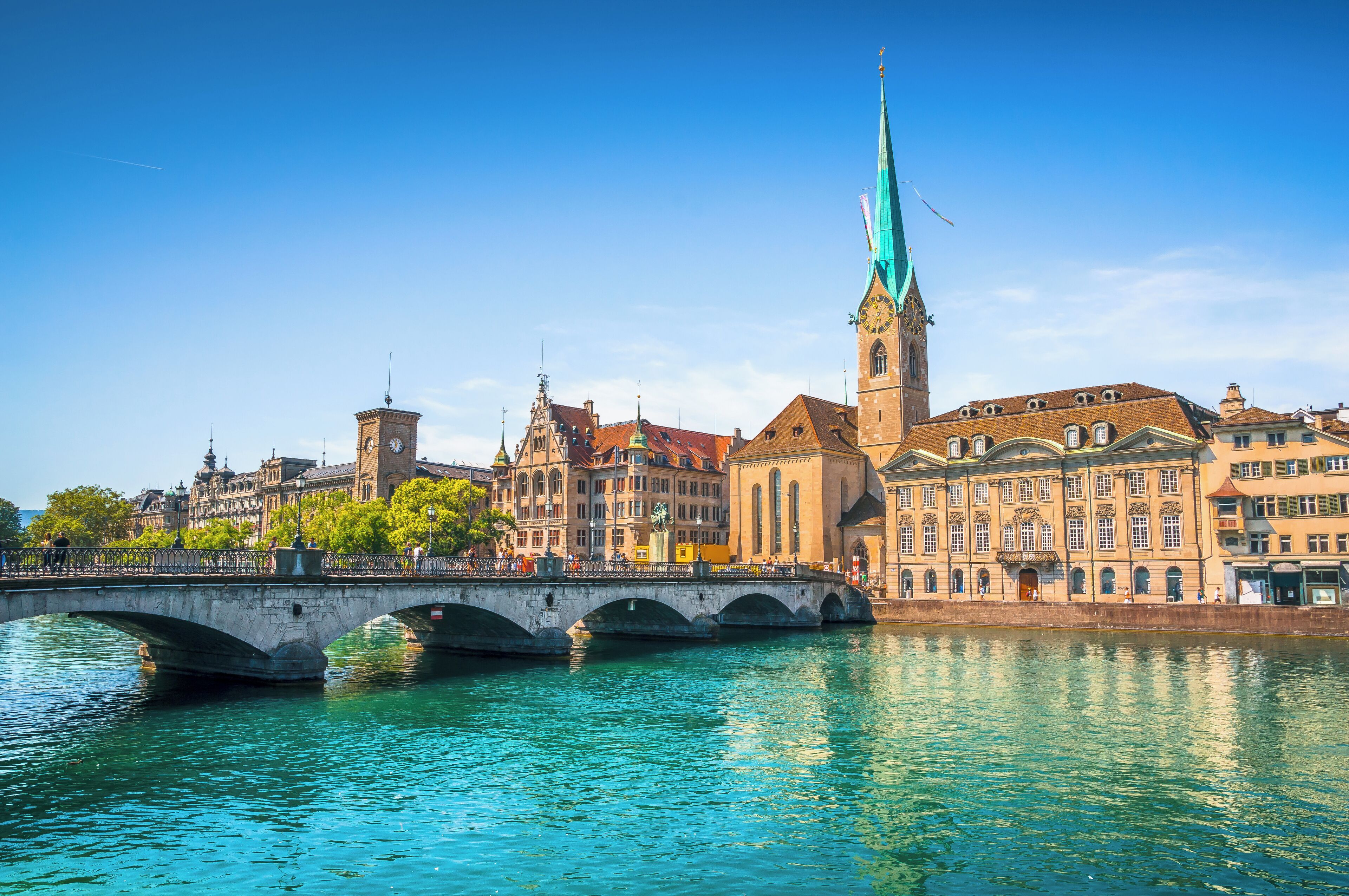 A bridge over a river with historic buildings and a tall church spire.