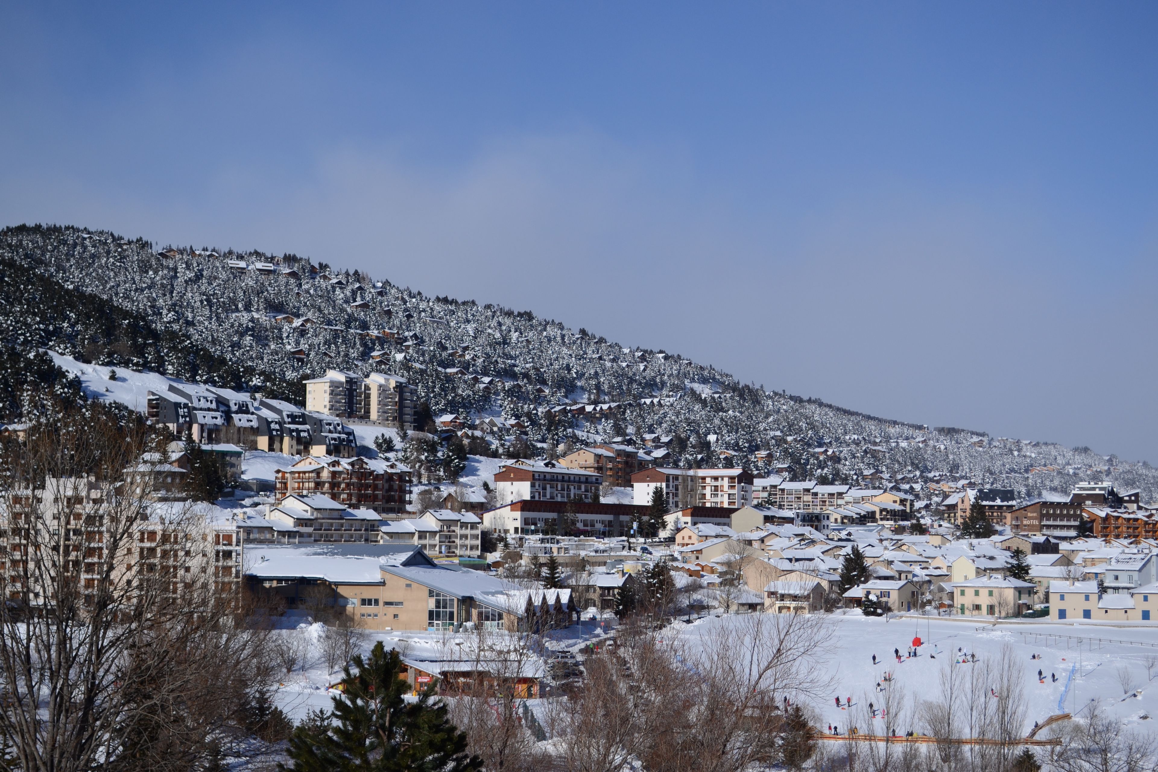 A snow-covered town with buildings and a ski slope.