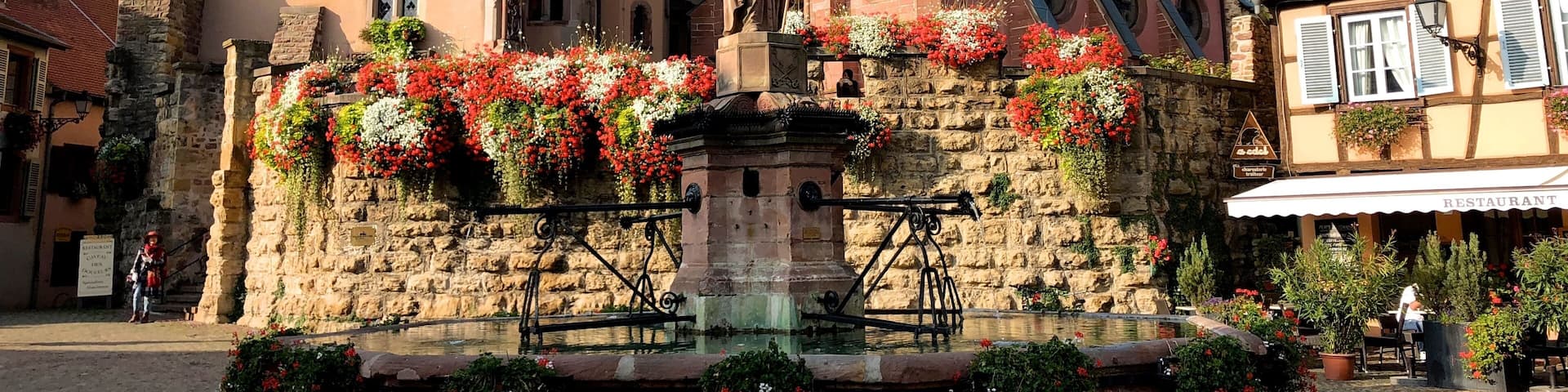 Designated as one of France's "Plus Beaux Villages," the picture-perfect village of Eguisheim is nestled in a sunny valley surrounded by the green rolling foothills of the Vosges Mountains. This enchanting medieval village was founded in 720 by the Count Eberhard. Just a short distance from Colmar, this typical Alsatian village has narrow cobblestone streets lined with brightly painted half-timbered houses that date from the 16th and 17th century. Ancient inscriptions can still be deciphered on the stone lintels of the houses. These historic houses feature balconies that are lovingly decorated with potted flowers. Because of its exquisite floral displays, the village has been rewarded with the "Grand Prix National du Fleurissement," France's most prestigious national floral award. Visitors will enjoy wandering through the village, admiring the beauty of the buildings, and the colorful geranium-bedecked window sills.