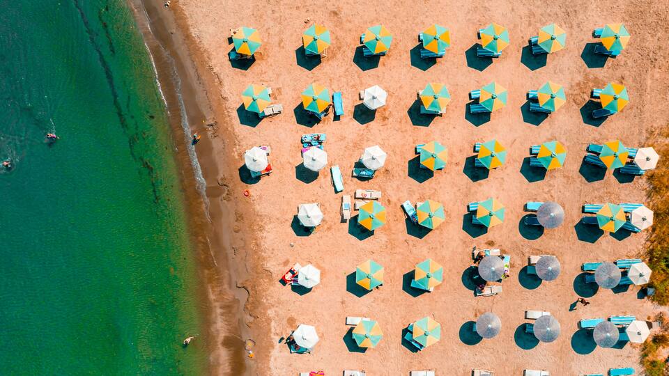 An aerial view of a beach with rows of umbrellas and beach chairs.