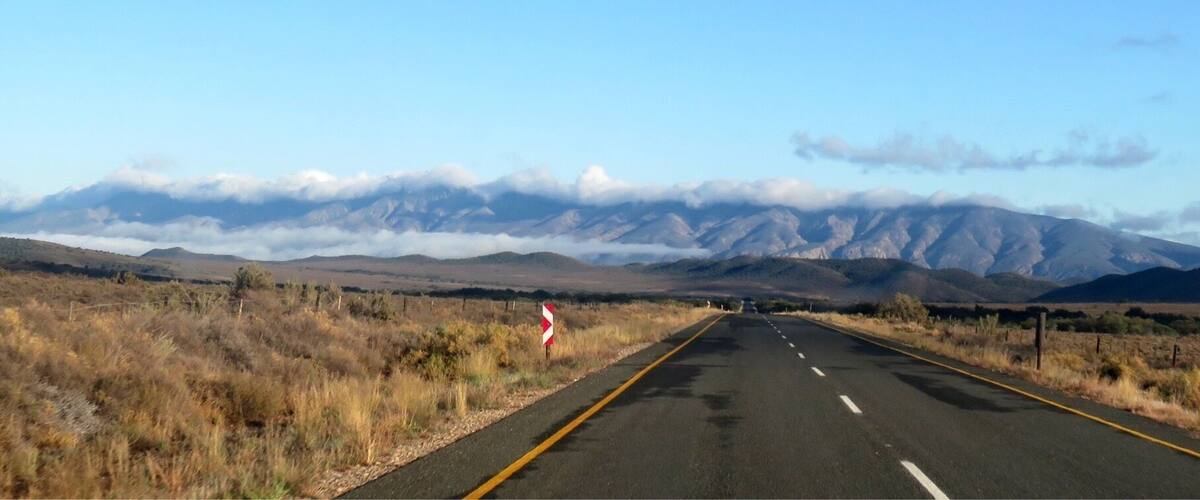 A straight road with mountains in the distance and a clear sky.