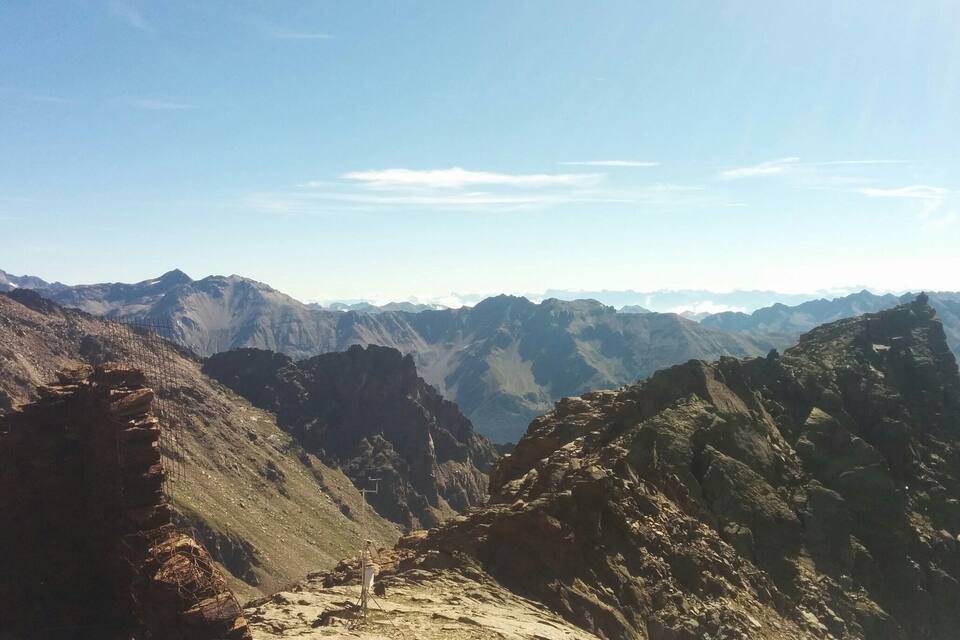 Paesaggio montuoso con terreno impervio e cielo sereno.