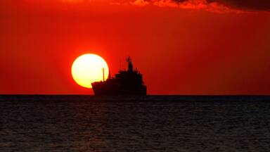 Tombeau Bay, Baie-du-Tombeau, Pamplemousses District, Mauritius, Mascarene Islands, Africa - sunset over Indian Ocean with distant ship seen from Tombeau Bay close to Port Louis and its harbour