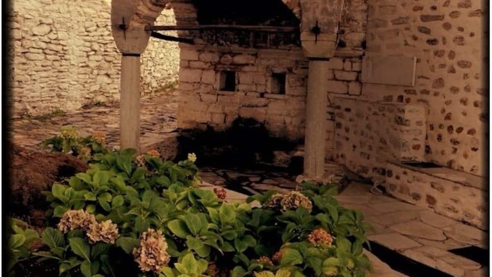A stone archway, a stone wall, and a garden with hydrangea plants.