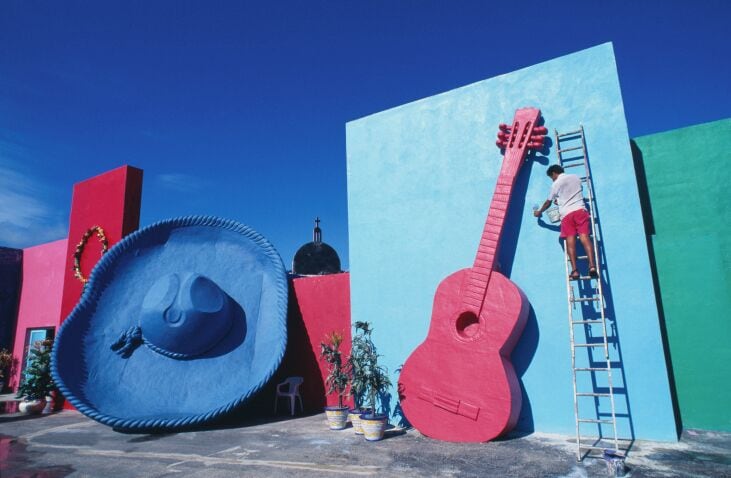 Man painting oversized guitar, outdoors