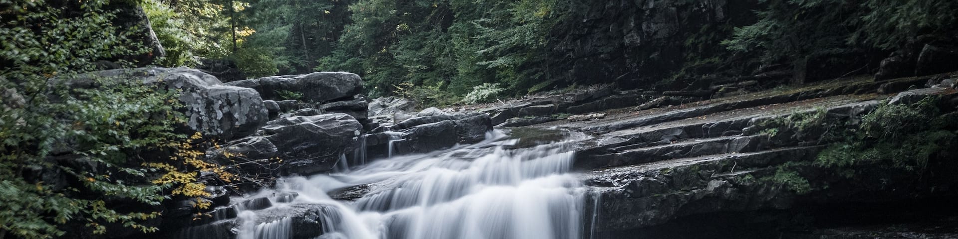 A waterfall cascading over rocks in a forested area.