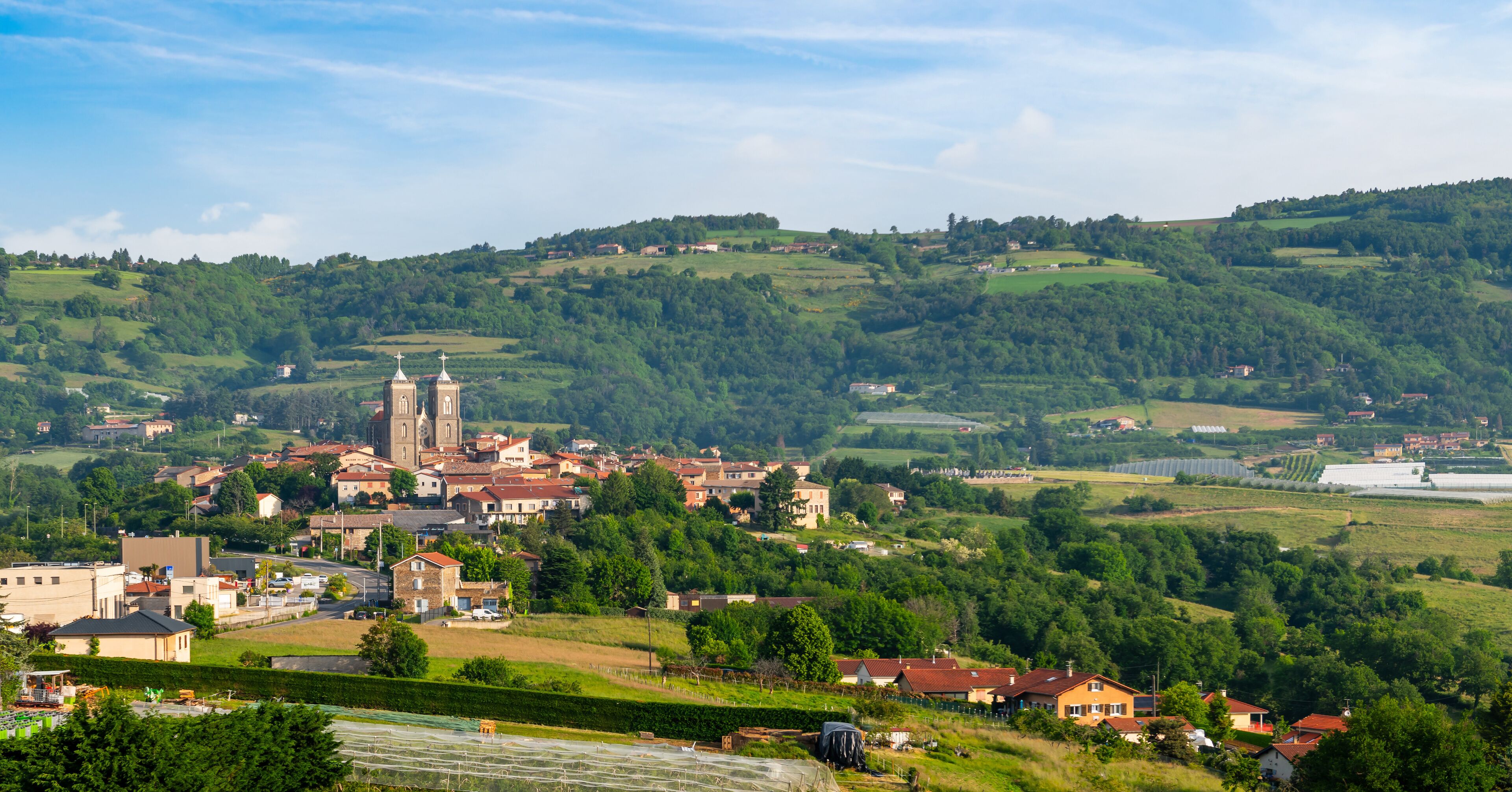A town nestled in a valley with a prominent church and rolling hills in the background.