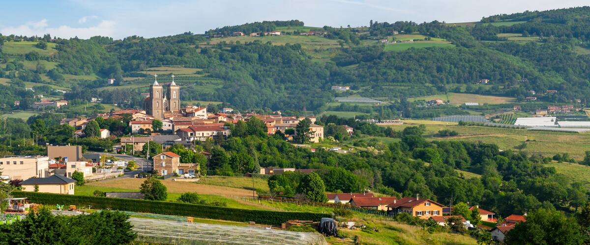 A town nestled in a valley with a prominent church and rolling hills in the background.