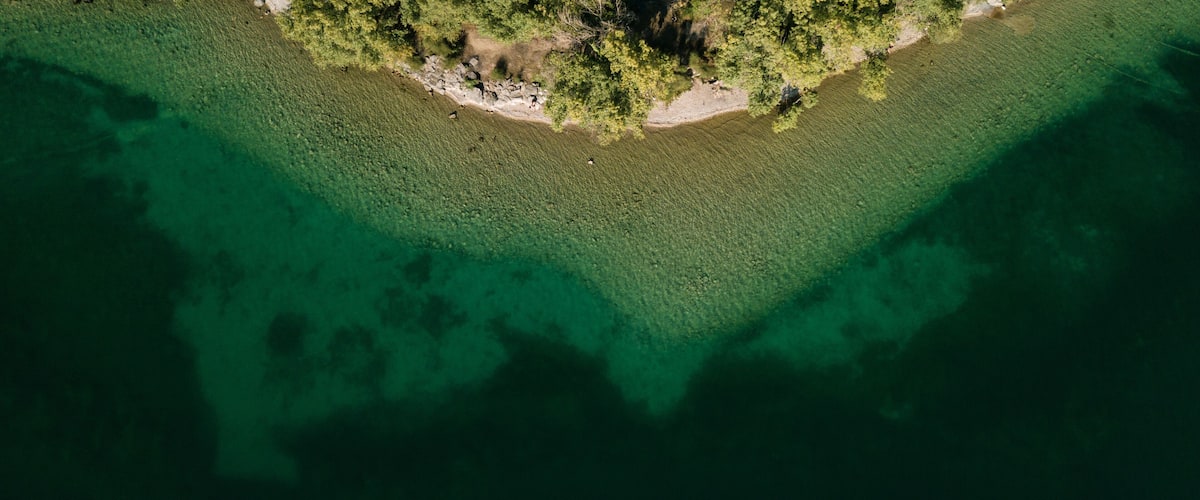 An aerial view of a small island with clear waters and dense vegetation.