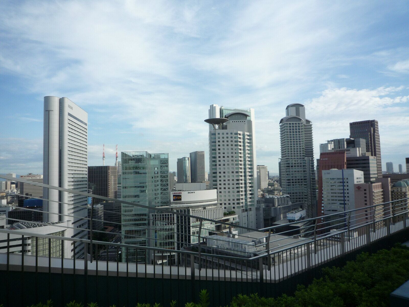 A cityscape with modern skyscrapers, including a Sony building, under a partly cloudy sky.