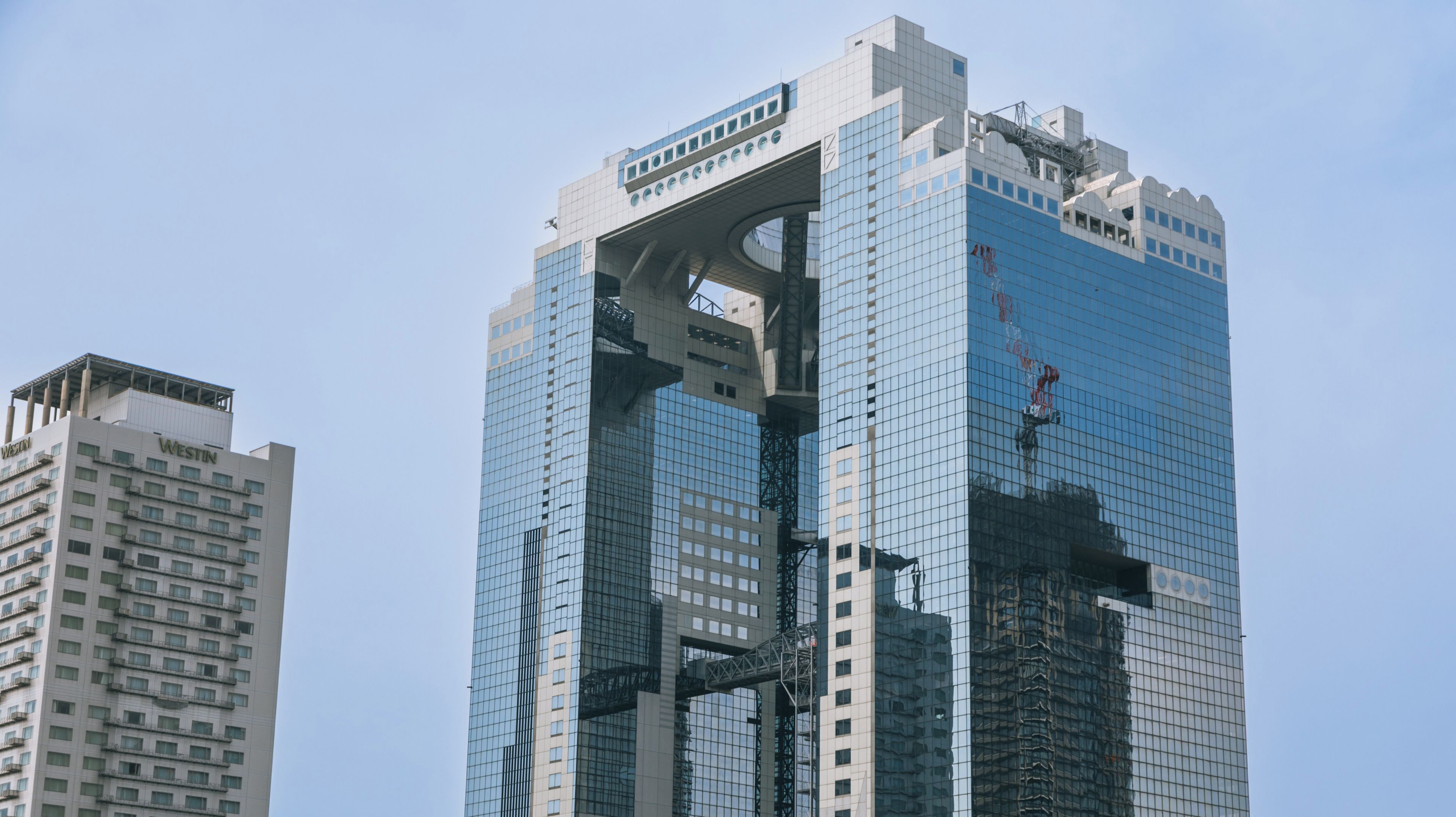 A modern skyscraper with a unique architectural design, featuring a large overhang and a glass facade.