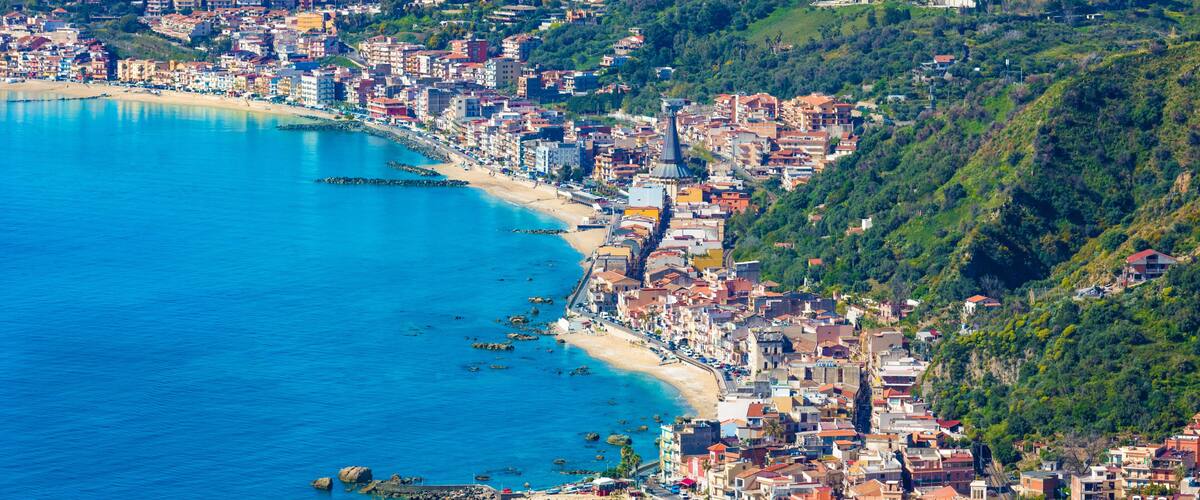 A coastal city with a beach, dense urban area, and a hilly landscape.