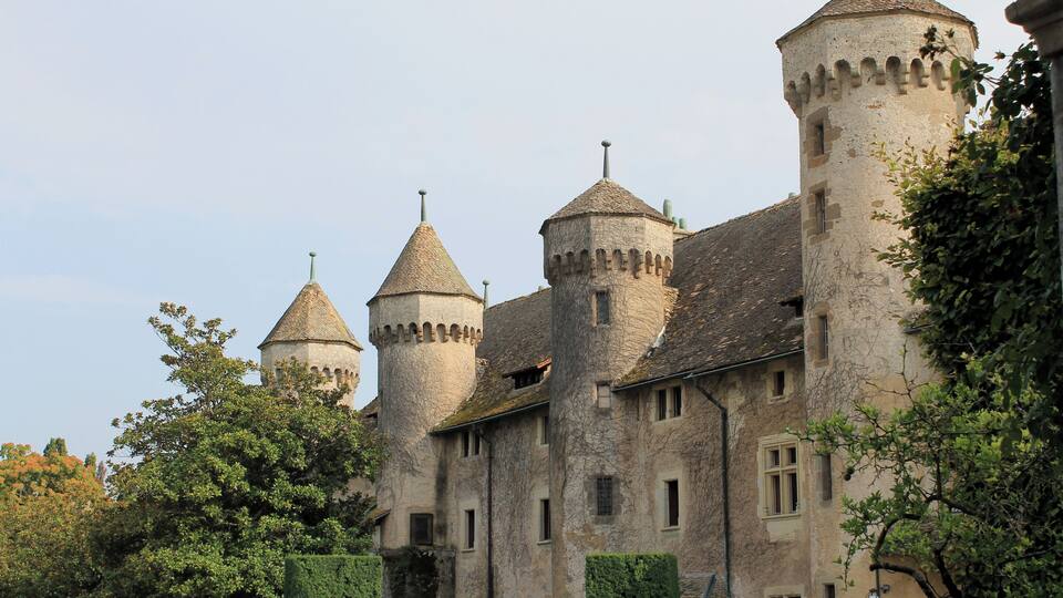 A historic castle with multiple towers and a well-maintained garden.