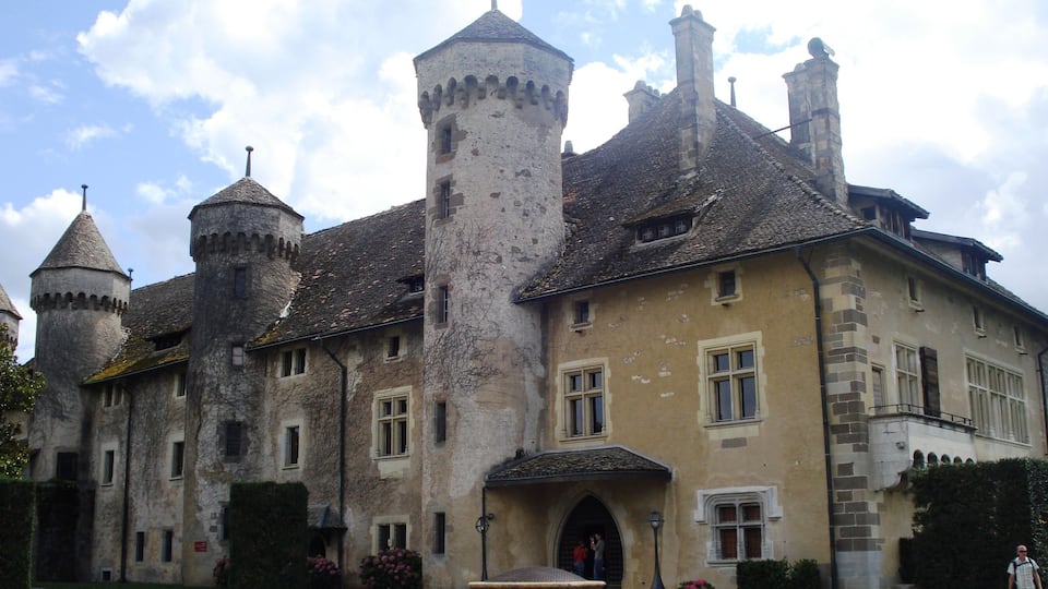 A historic castle with multiple towers, a central courtyard, and a well-maintained garden.