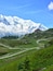 A snow-capped mountain, a winding road, and a building on a hillside.