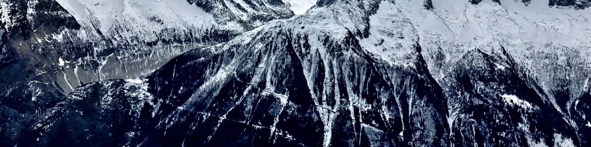 A snow-covered mountain range with a valley and a road running through it.