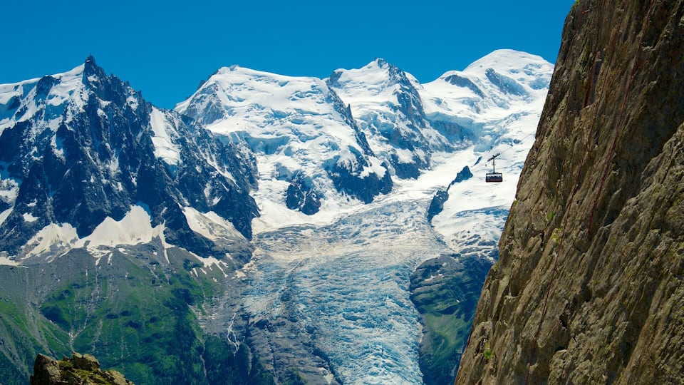 A glacier with snow-covered mountains in the background and a cable car in the midground.