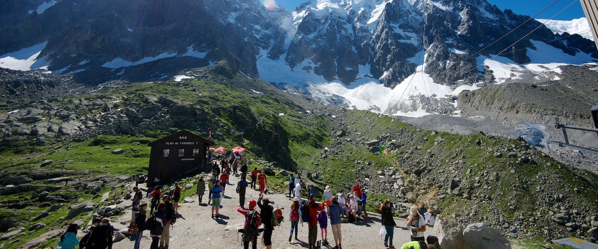 A mountain landscape with a bar named "Plan de l'Aiguille" and a crowd of hikers.