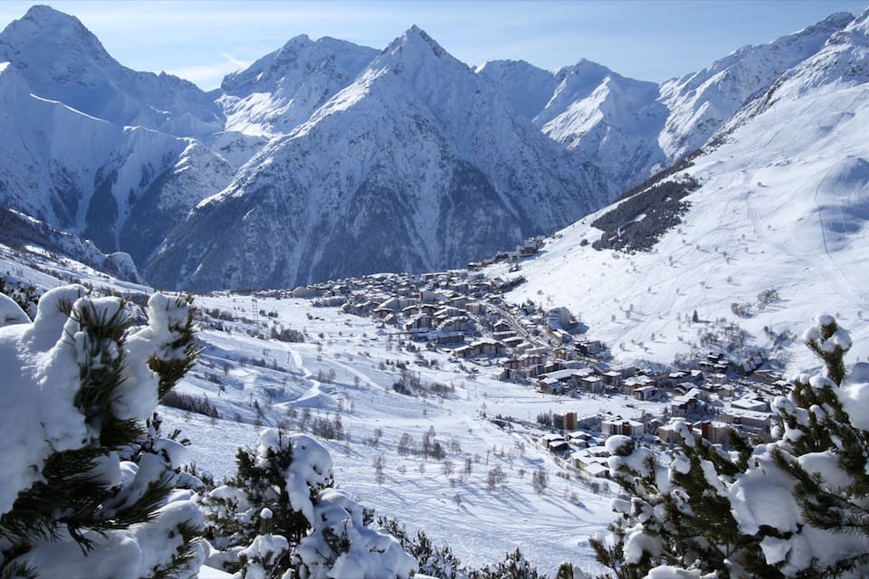 Una catena montuosa innevata con una stazione sciistica nella valle.