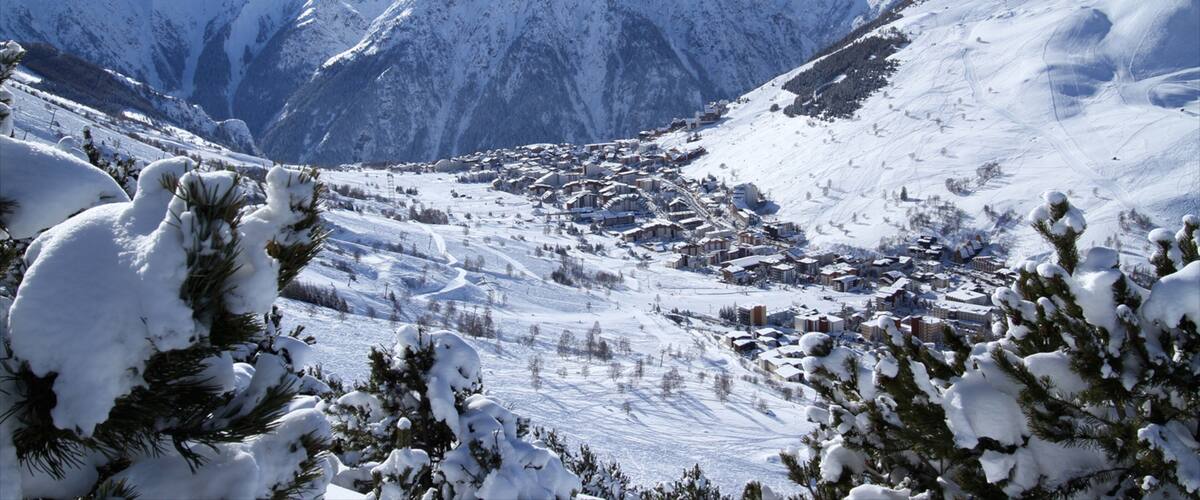 A snow-covered mountain range with a ski resort in the valley.