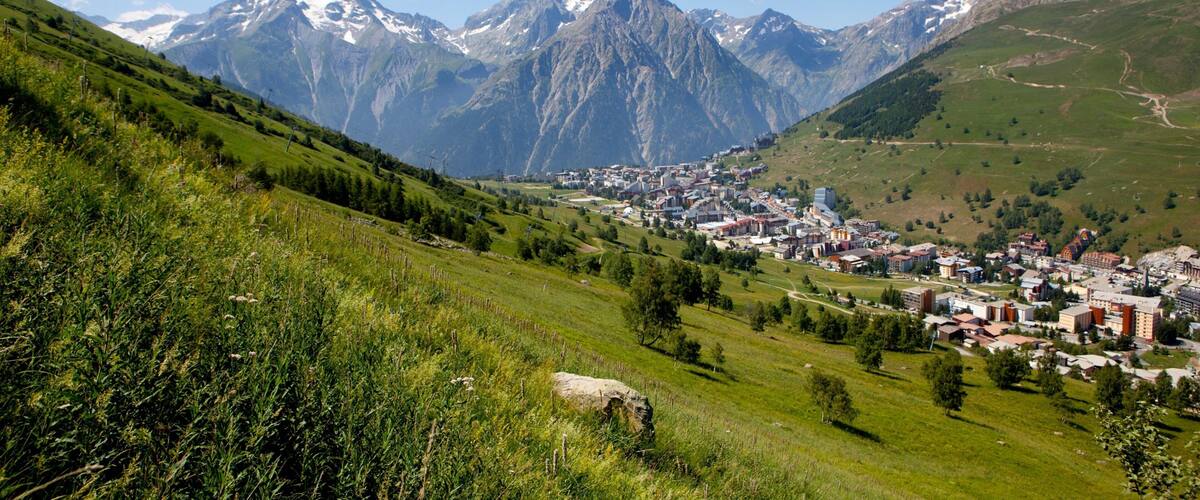 A town nestled in a valley with snow-capped mountains in the background.