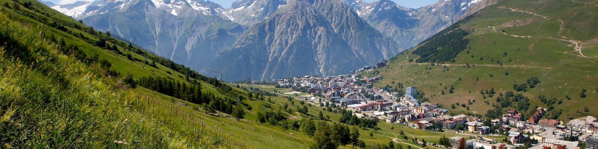 A town nestled in a valley with snow-capped mountains in the background.