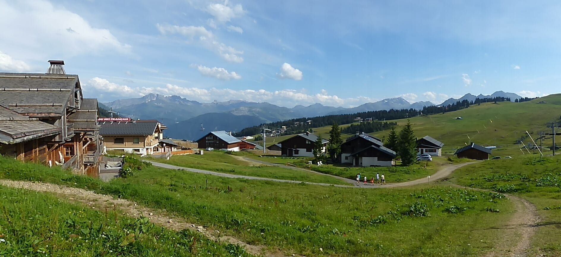 A rural village with wooden houses, a clear sky, and mountains in the background.