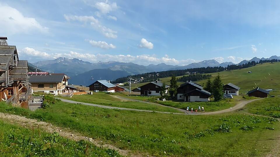 A rural village with wooden houses, a clear sky, and mountains in the background.