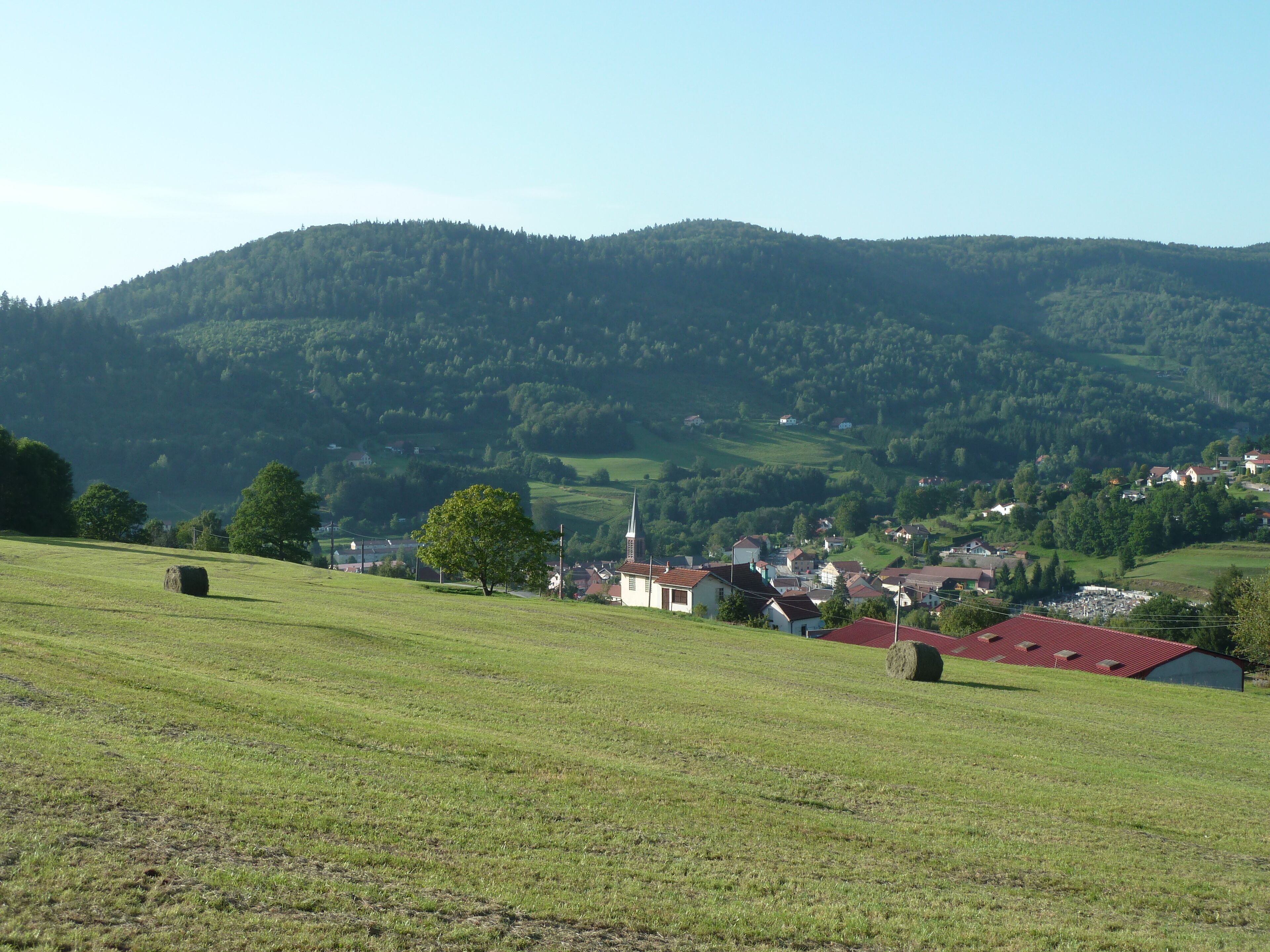 A rural landscape with rolling hills, a church, and scattered houses.