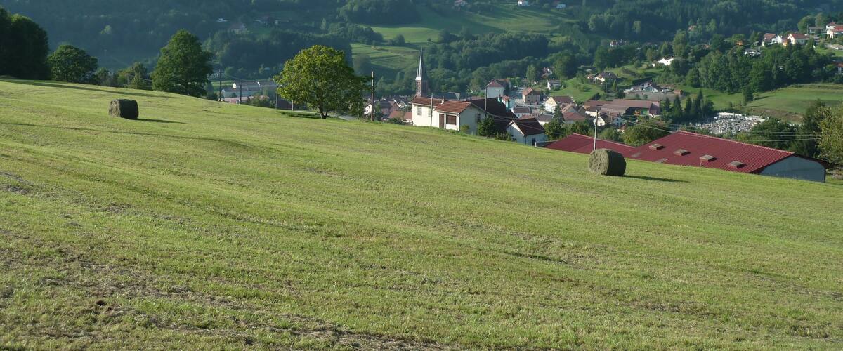 A rural landscape with rolling hills, a church, and scattered houses.