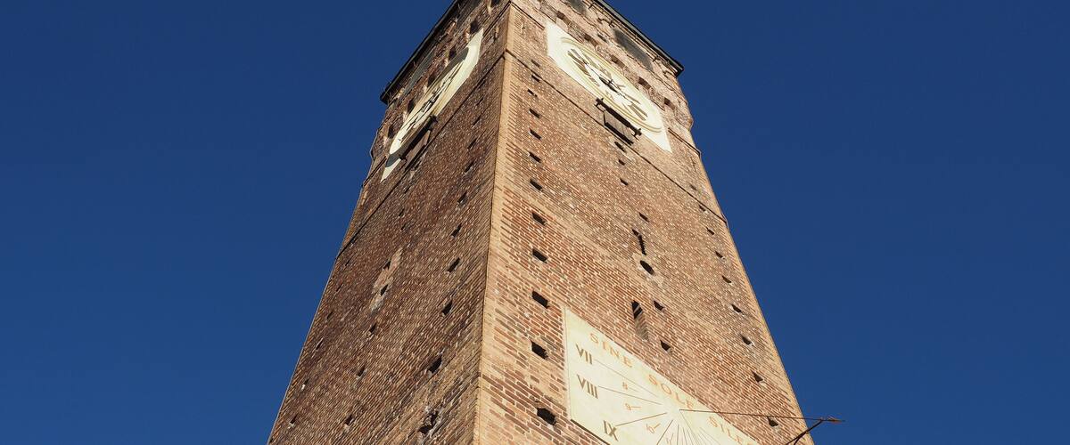 A tall brick tower with a large clock face and Roman numerals.