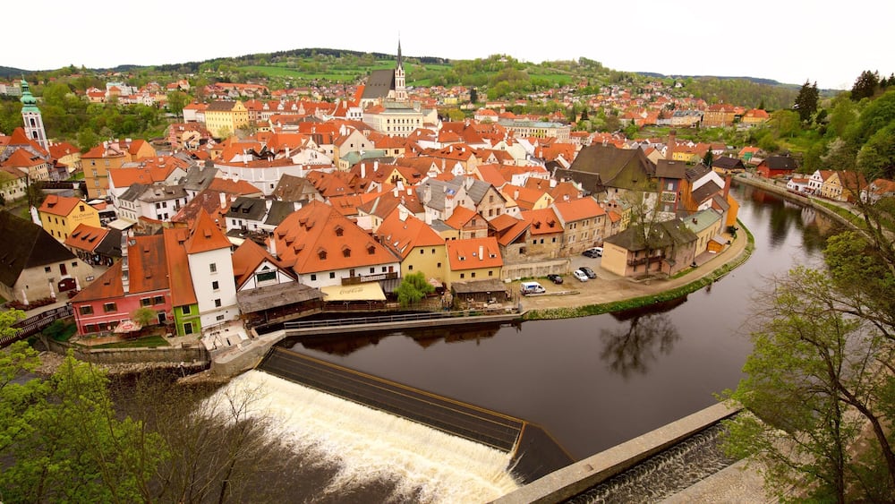 A river with a bridge, a town with red-roofed buildings, and a church with a spire.