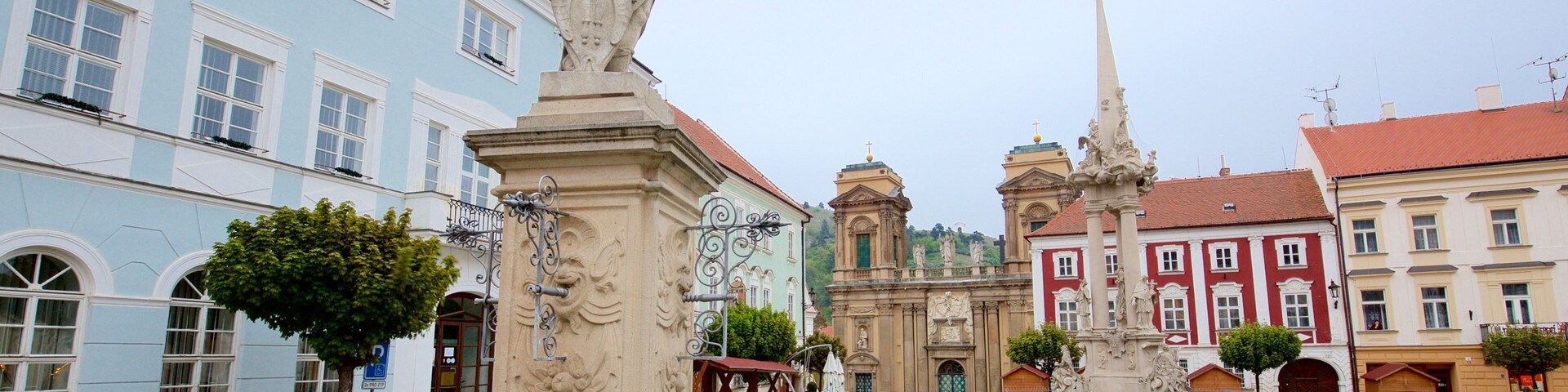 A historic square with a fountain, a statue, and classical architecture.