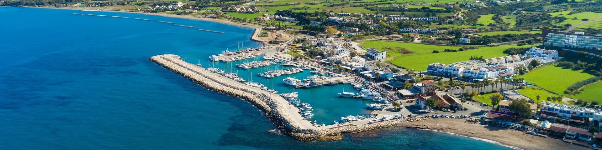 Aerial bird's eye view of Latchi port, Akamas peninsula, Polis Chrysochous, Paphos,Cyprus. Latsi harbour with boats and yachts, fish restaurant, promenade, beach tourist area and mountains from above