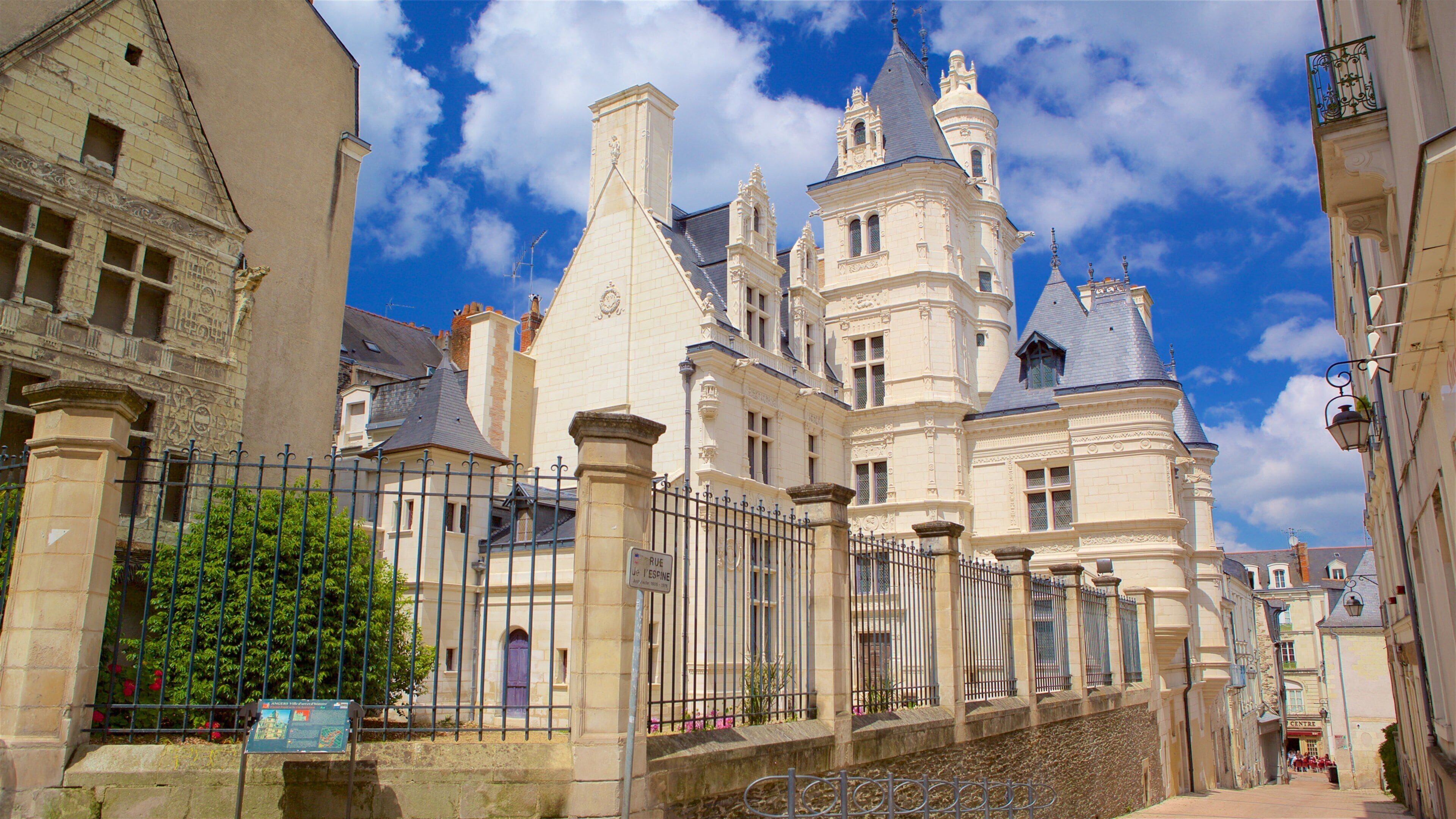 A historic building with ornate architecture, a wrought iron fence, and a clear blue sky.
