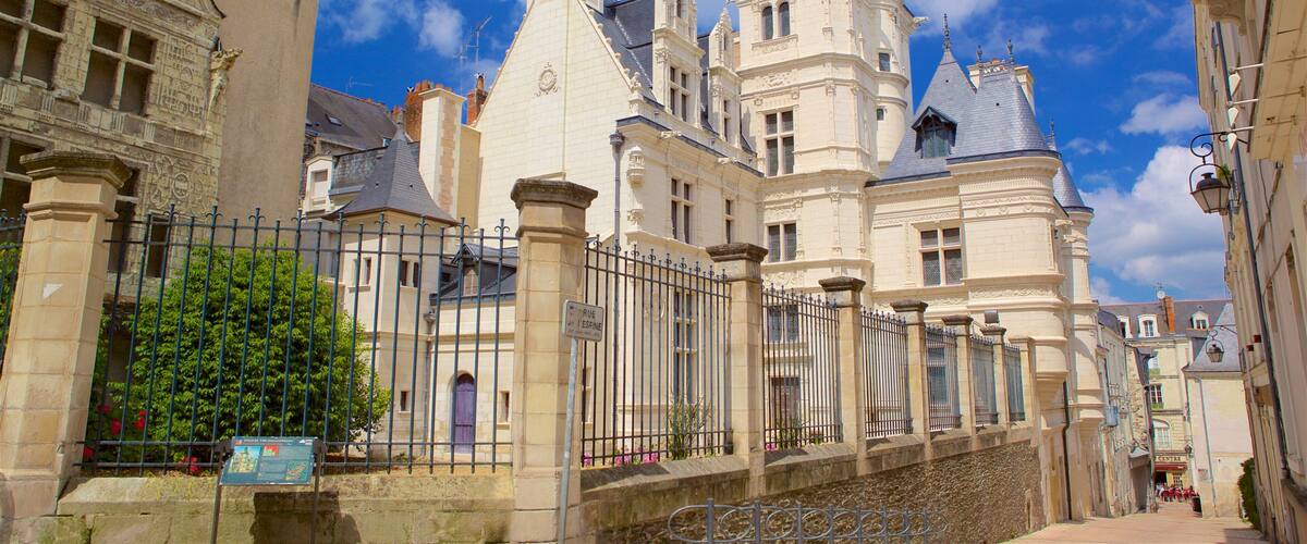 A historic building with ornate architecture, a wrought iron fence, and a clear blue sky.