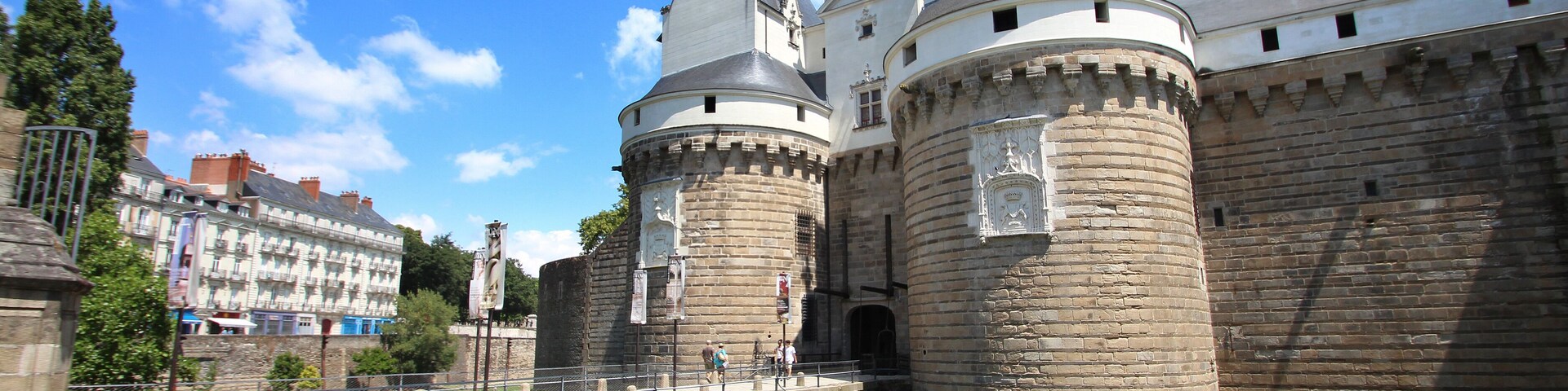 Um castelo histórico com um fosso, uma ponte e um rio.