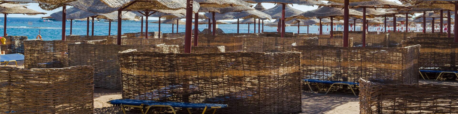 Rows of straw umbrellas from the sun, stretching into the distance on a wide beach on the Red Sea, Makadi Bay, Hurghada, Egypt.