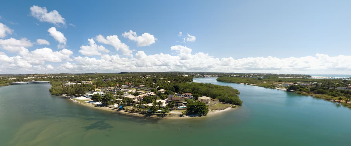 An aerial view of a coastal town with a river, surrounded by greenery and a clear sky.
