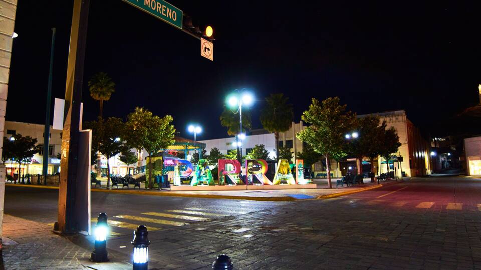 downtown at night, street in front of a park and sign with the name of the place, parral chihuahua