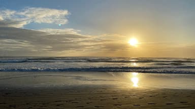 A beach with footprints and waves at sunset.