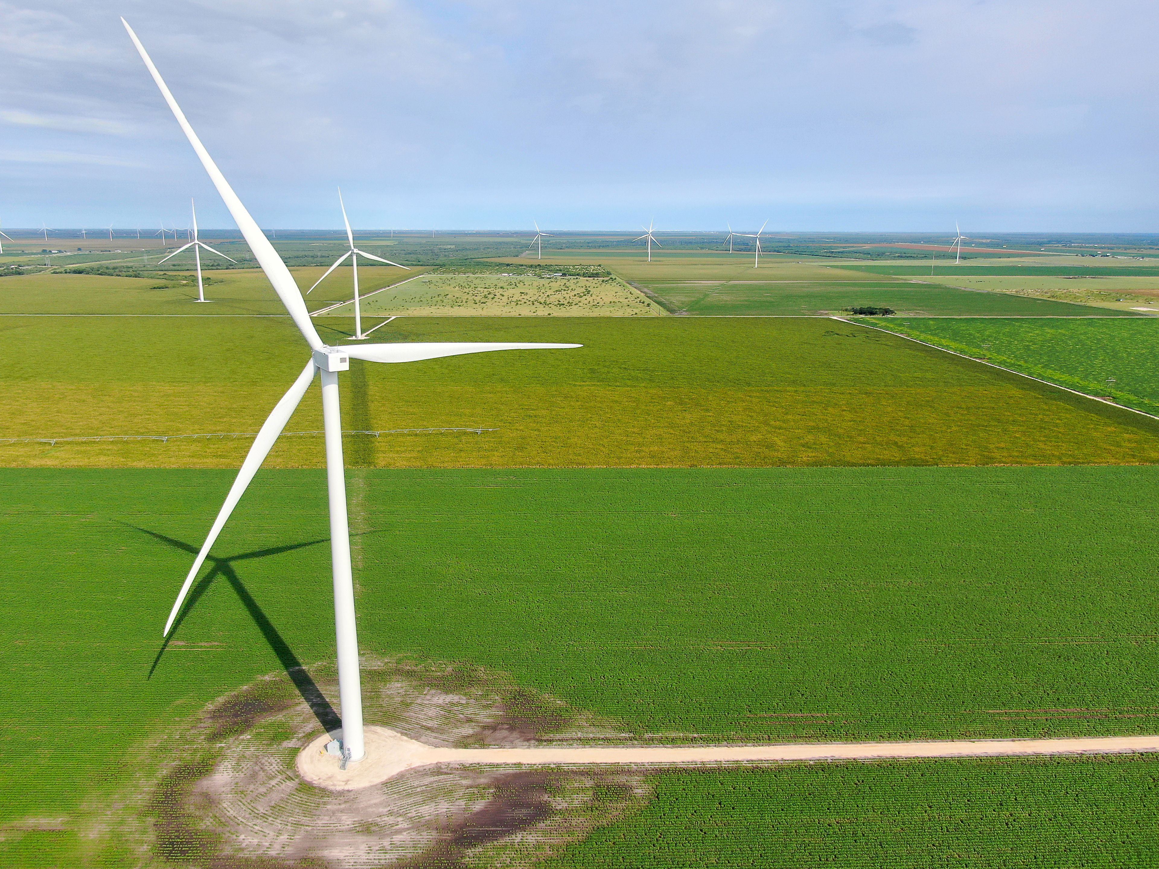 Een windmolenpark met meerdere windturbines in een groen landschap.