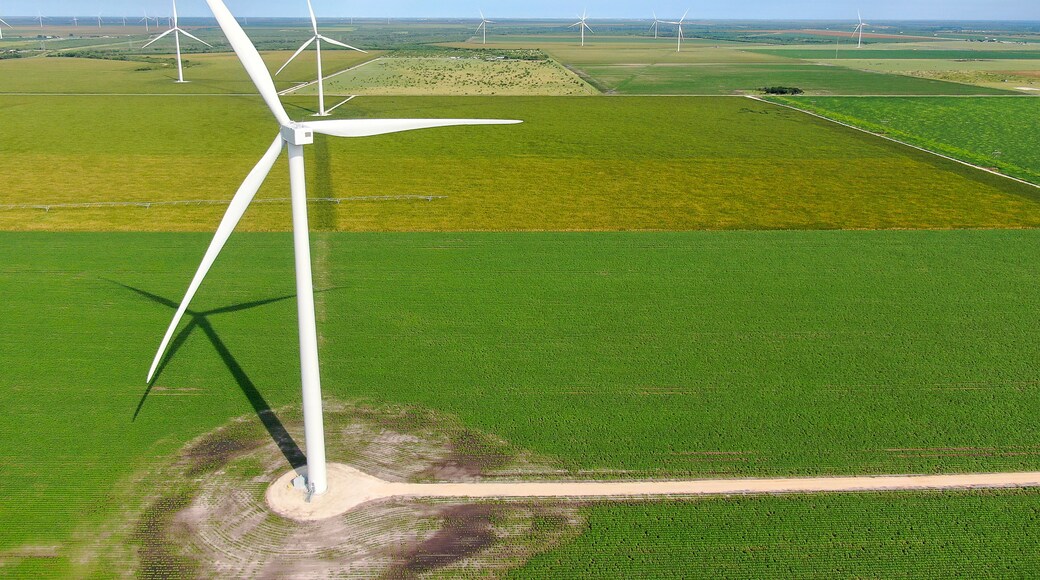 Een windmolenpark met meerdere windturbines in een groen landschap.