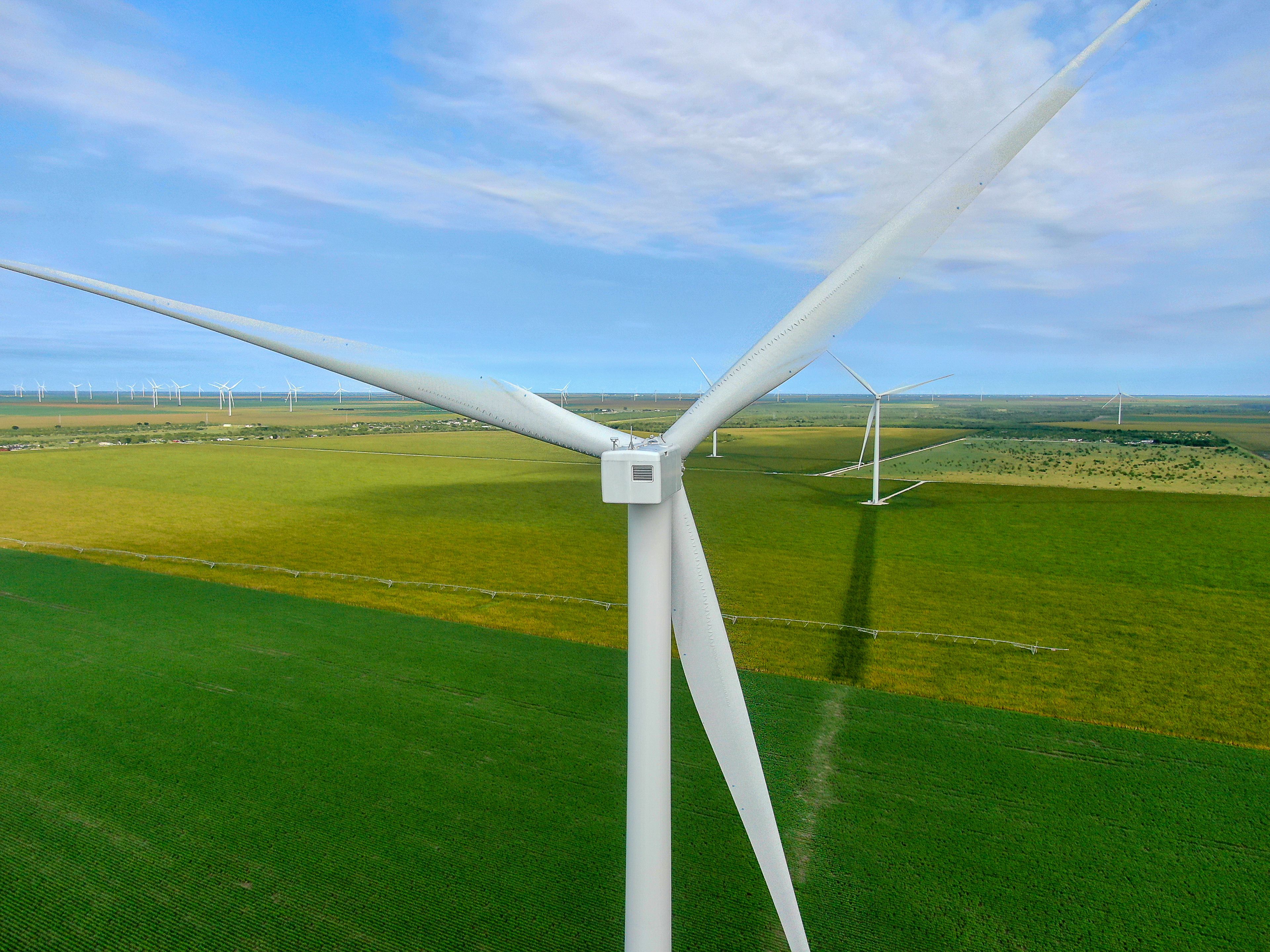 Een windturbine met meerdere bladen in een groen veld, met andere windturbines op de achtergrond.