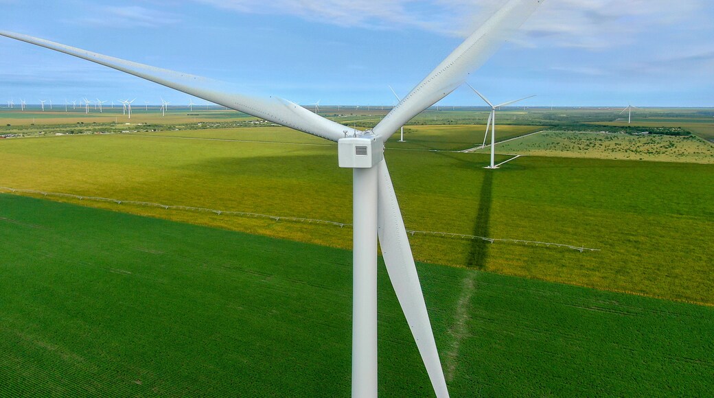 Een windturbine met meerdere bladen in een groen veld, met andere windturbines op de achtergrond.