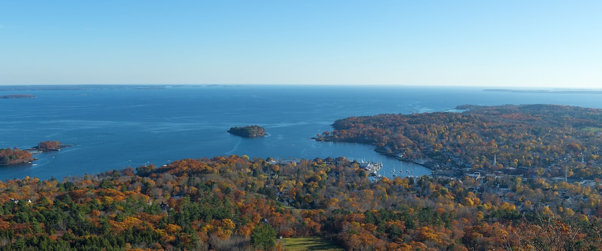 A coastal landscape with autumn foliage, a bay, and a small town.