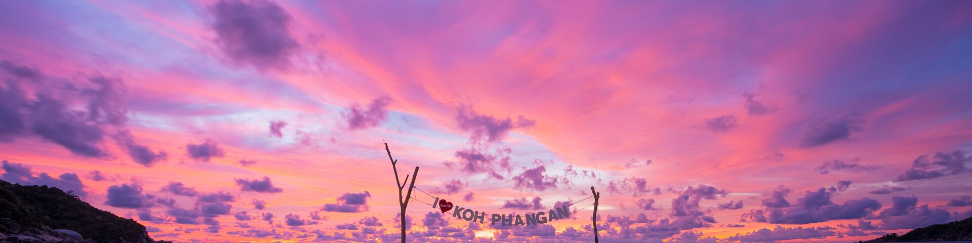 Una playa al atardecer con un cielo en tonos rosados y morados, y un reflejo sobre la arena mojada.