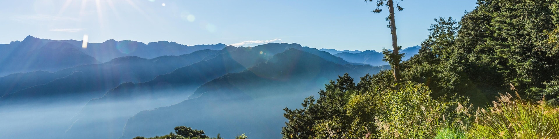 KJNPAN Morning view of shining sun on clear blue sky over complicated mountain range at Zhushan forest, Alishan Recreation Area of Taiwan.