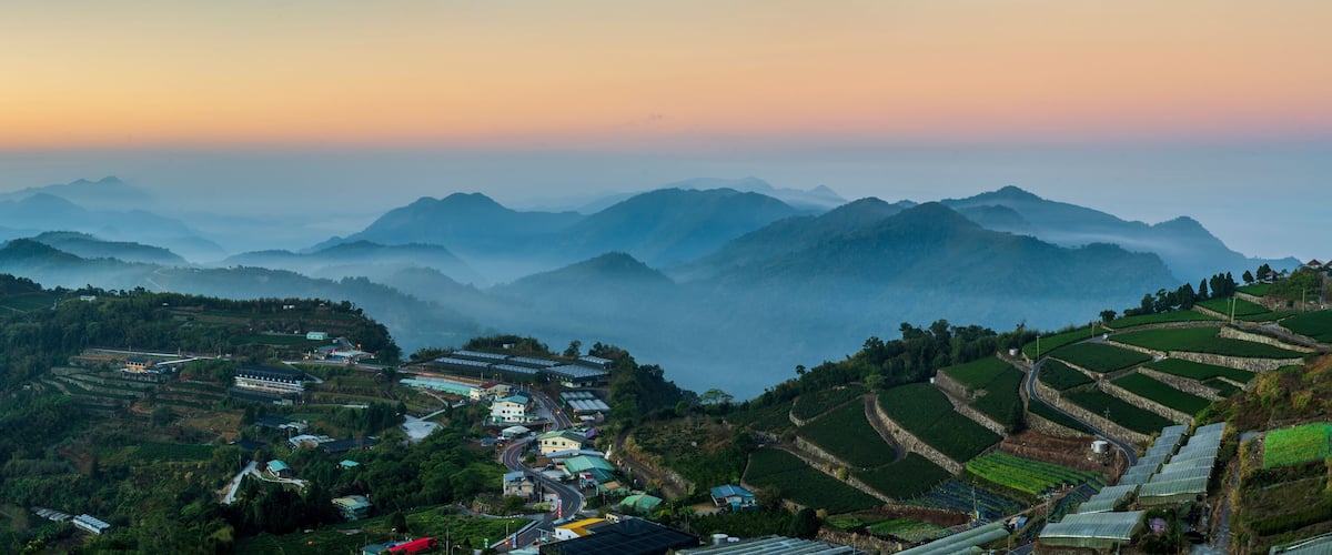 Terraced fields, a village, and mountains in the background.